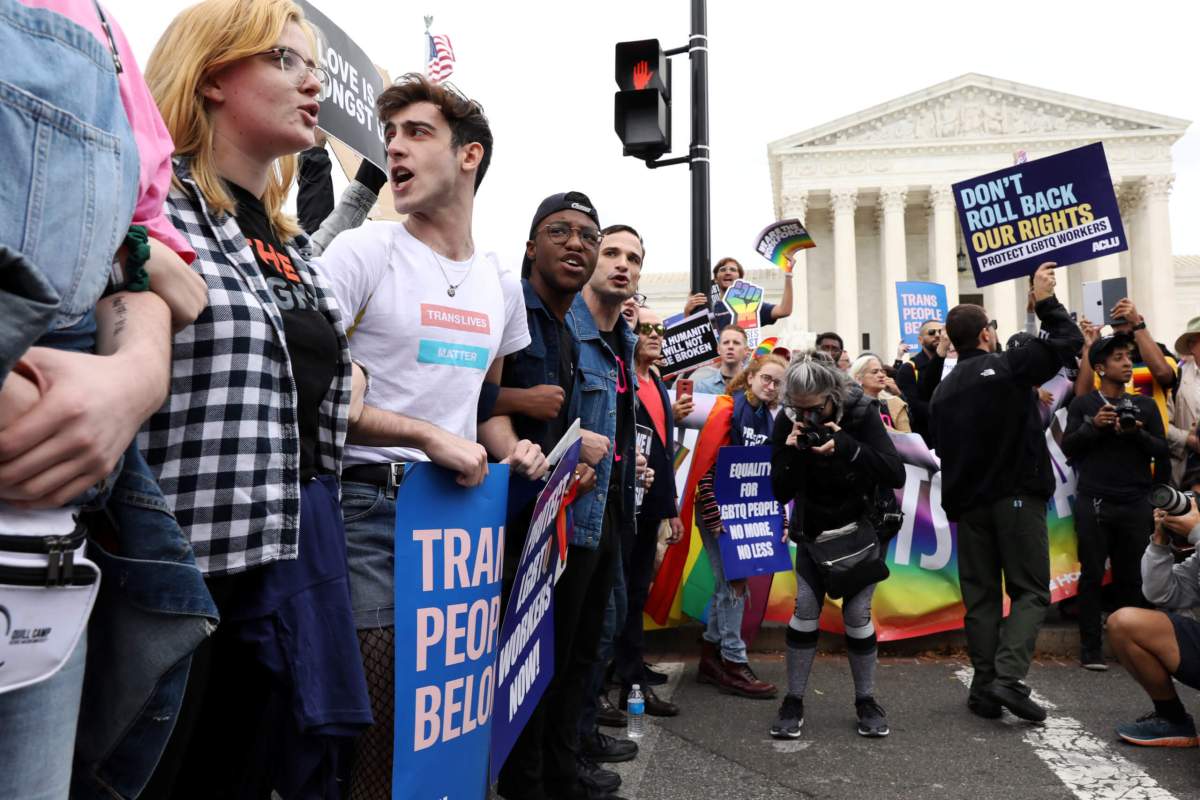 LGBTQ activists and supporters block the street outside the U.S. Supreme Court as it hears arguments in a major LGBT rights case in Washington