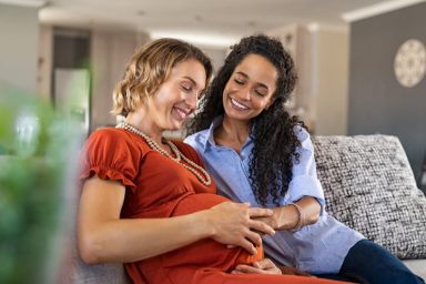 Happy woman hugging her pregnant girlfriend