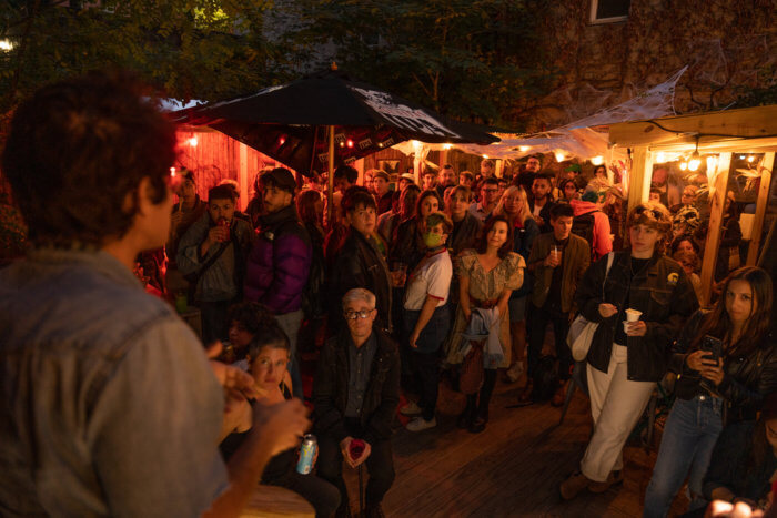 Queer Soup Night founder and organizer, Liz Alpern, welcomes a packed house to the monthly roving dinner event hosted at Ginger's Bar in Brooklyn in October 2022.