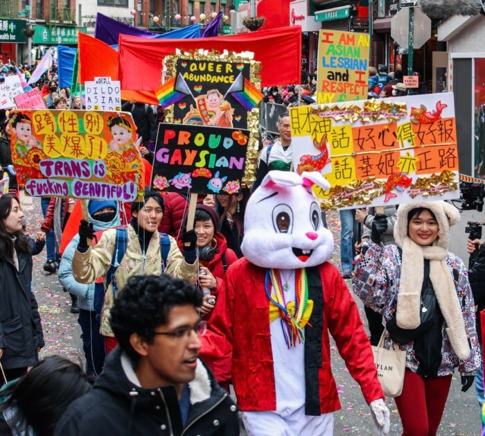 A sea of signs with LGBTQ-inclusive messages wave through the air.