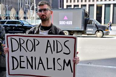 Activist Jason Rosenberg holds up a sign outlining ACT UP's core demand to Simon & Schuster.