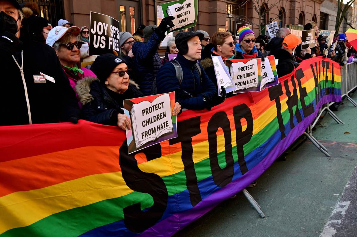 Supporters unfurl a long Rainbow Flag emblazoned with the phrase "STOP THE HATE."