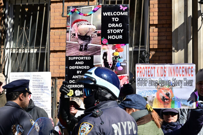 Bigots flash signs denouncing drag story hour.