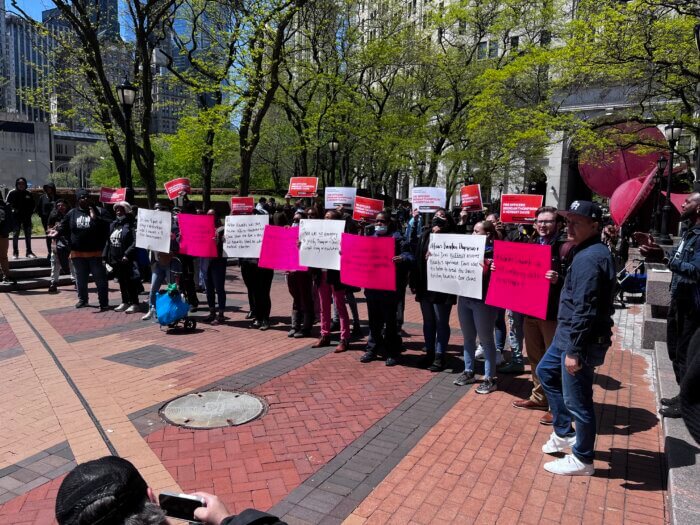 Advocates hold signs outside 1 Police Plaza on April 24.