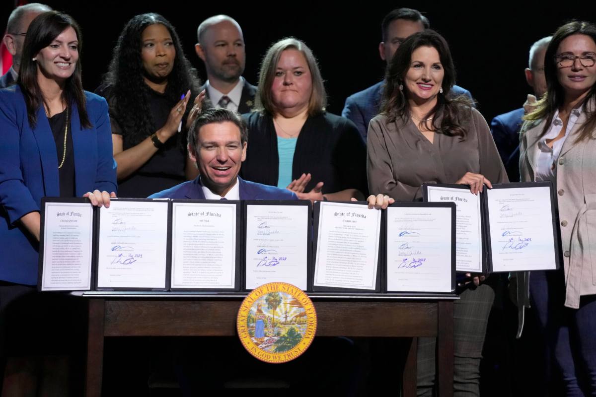 Florida Gov. Ron DeSantis holds up bills he signed during a bill signing ceremony at the Coastal Community Church at Lighthouse Point, Tuesday, May 16, 2023, in Lighthouse Point, Fla.