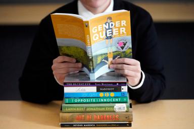 Amanda Darrow, director of youth, family and education programs at the Utah Pride Center, poses with books that have been the subject of complaints from parents on Dec. 16, 2021, in Salt Lake City.