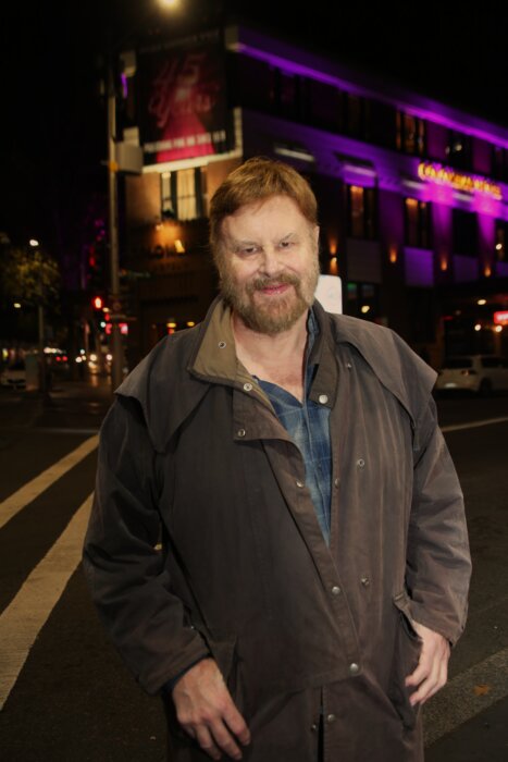 Native New Yorker Lawrence Gibbons, the publisher of the LGBTQ+ publication Star Observer, in front of the Colombian Hotel, its façade adorned with a banner commemorating his paper’s 45th anniversary in Darlinghurst, Sydney’s main gay neighborhood. 