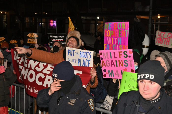 Jay W. Walker gestures while surrounded by others behind a barricade.