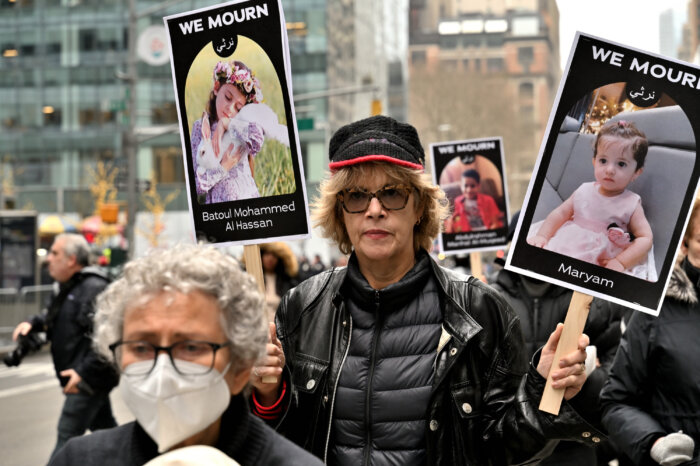 Laura Flanders, host of The Laura Flanders show on PBS, holds signs memorializing slain children.