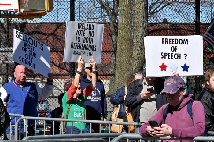 Demonstrators wave signs on the sidelines.